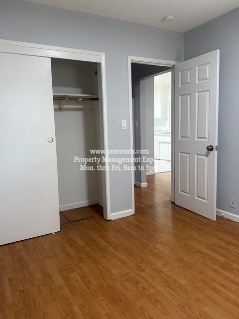 A room with a white door and a white closet with a white shelf.