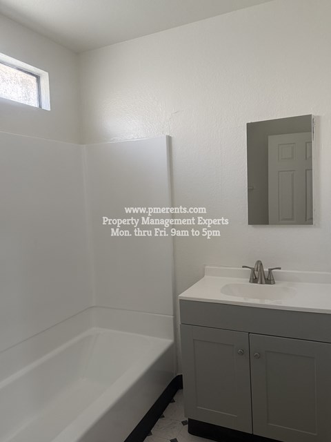 A white bathroom with a tub, sink and mirror.