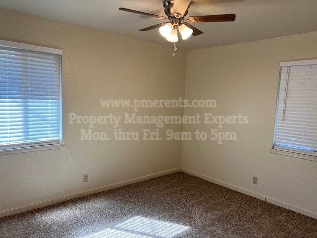 a bedroom with a ceiling fan and two windows