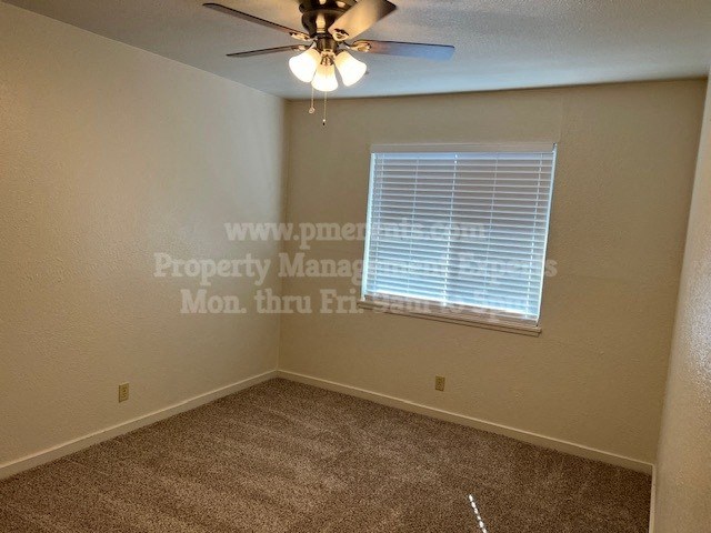 an empty bedroom with a ceiling fan and a window
