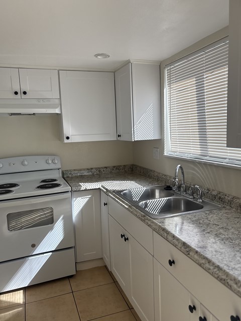 A kitchen with a white stove and white cabinets.