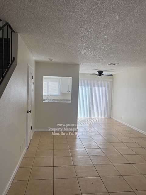 A room with a fan and a window with blinds.