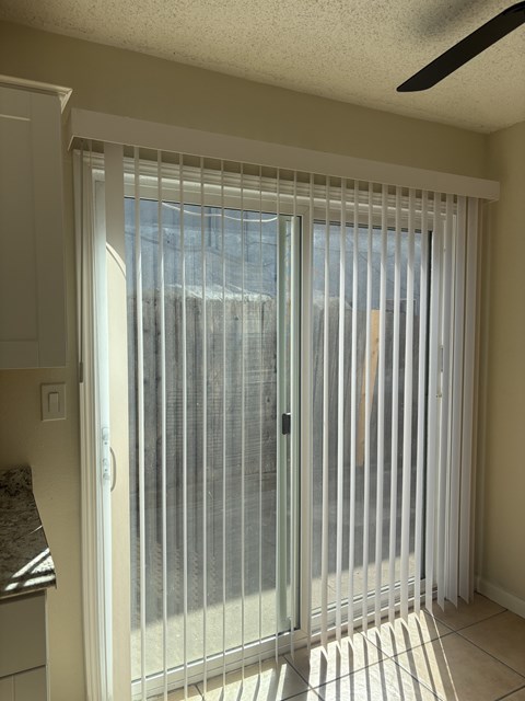 A sliding glass door with white blinds partially closed.