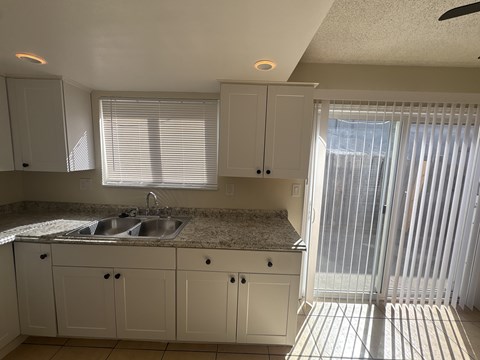 A kitchen with white cabinets and a granite countertop.