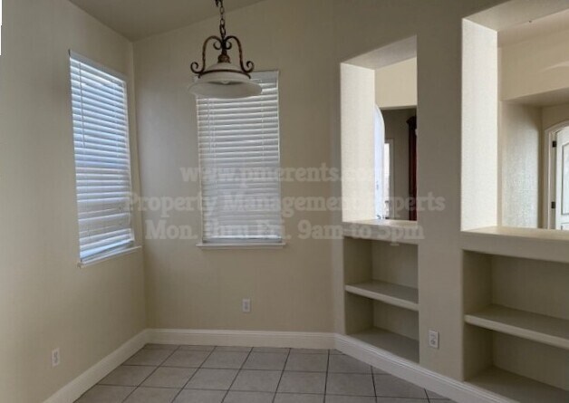 A room with a chandelier, shelves, and a window with blinds.
