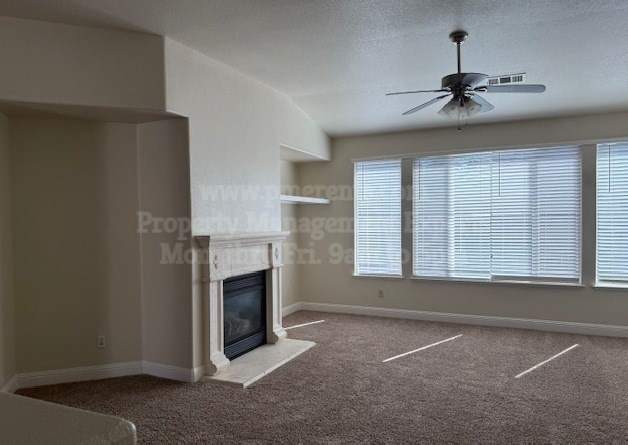 A living room with a fireplace and a fan on the ceiling.