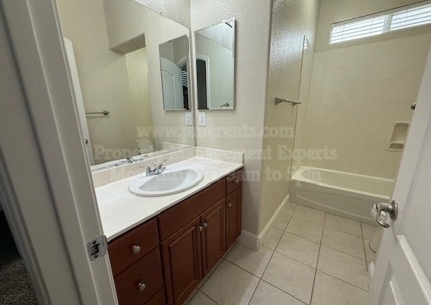 A bathroom with a sink, mirror, and a shower.