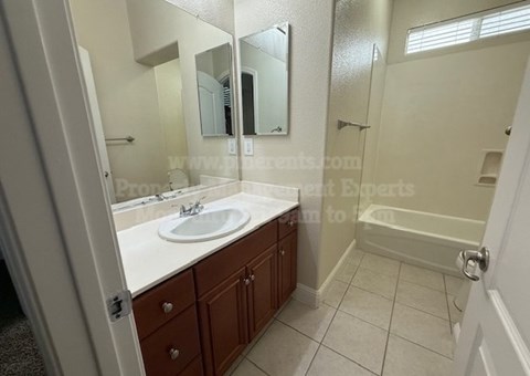 A bathroom with a sink, mirror, and a shower.