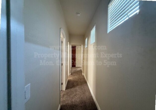 A long hallway with a carpeted floor and white walls.