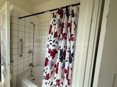 A shower curtain with a floral pattern hangs over a bathtub.