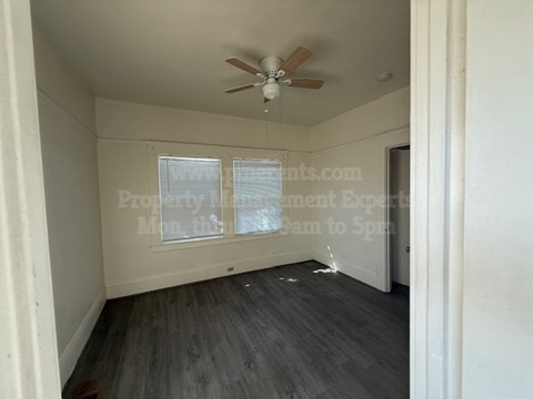 A room with a ceiling fan and wooden flooring.