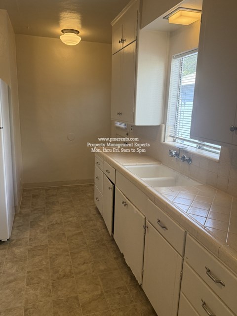 A bathroom with a tiled floor and white cabinets.