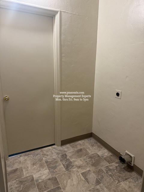 A white door with a gold handle is in a room with a tiled floor.