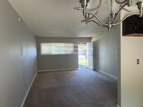 A room with a carpeted floor and a chandelier hanging from the ceiling.