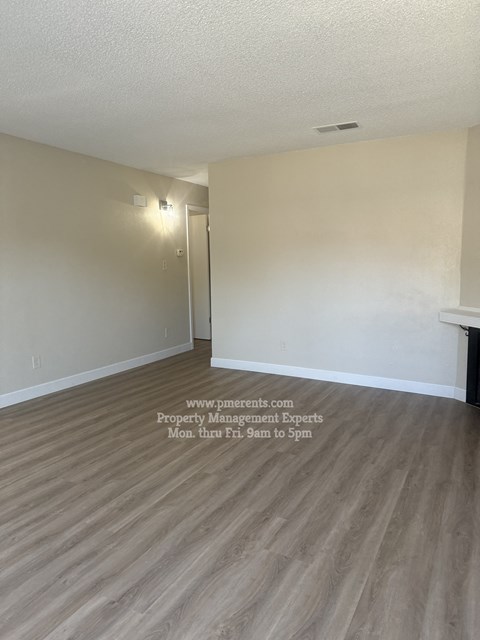 A room with a wooden floor and a door on the left side.