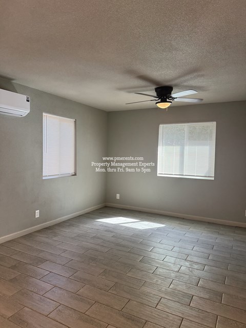 A room with a ceiling fan and a window with blinds.