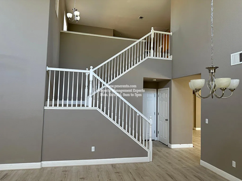 A staircase with a white railing and a chandelier hanging from the ceiling.
