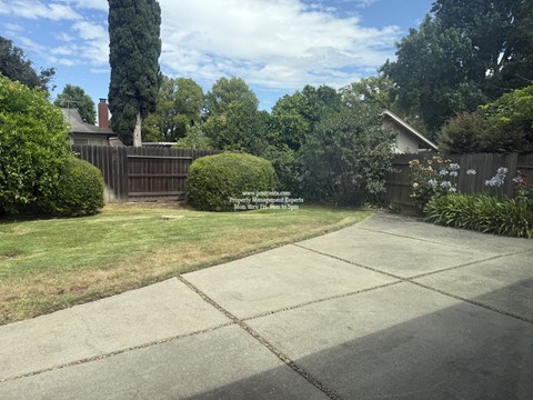 A backyard with a concrete patio and a wooden fence.