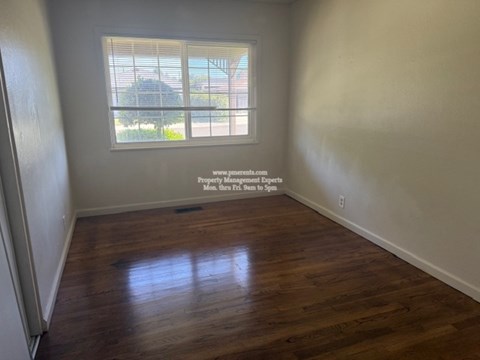 A room with a window and wooden flooring.