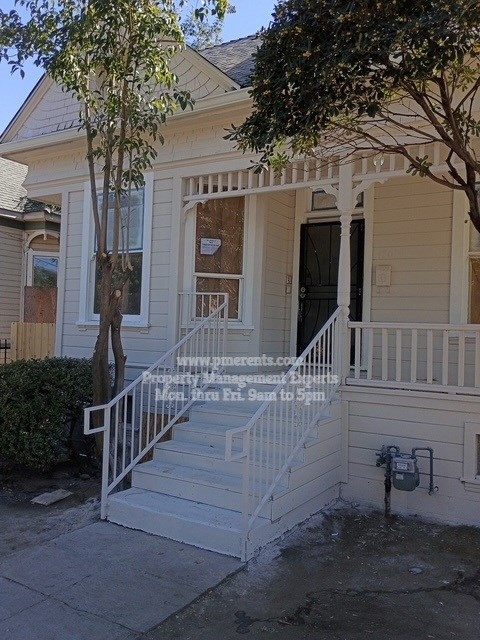A house with a porch and a tree in front.