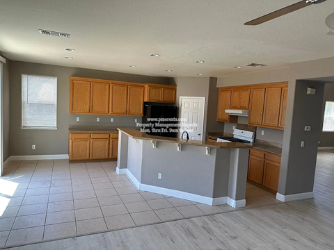 A kitchen with wooden cabinets and a countertop with a TV on it.