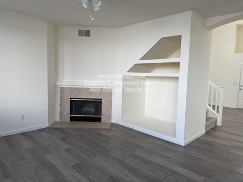 A living room with a fireplace and a staircase.