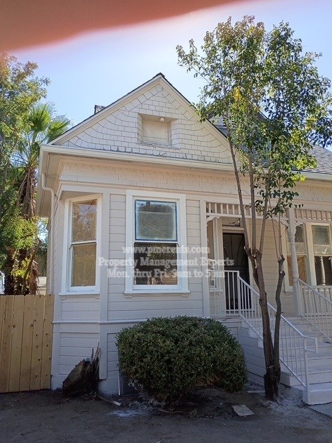 A house with a white facade and a tree in front.