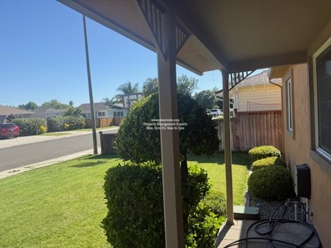 A view from a house looking out to a street with cars and other houses.