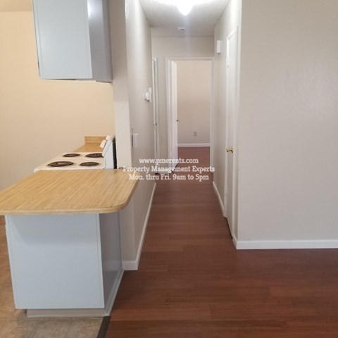 A long hallway with a wooden floor and white walls.