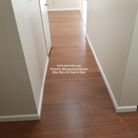 A hallway with wood flooring and white walls.