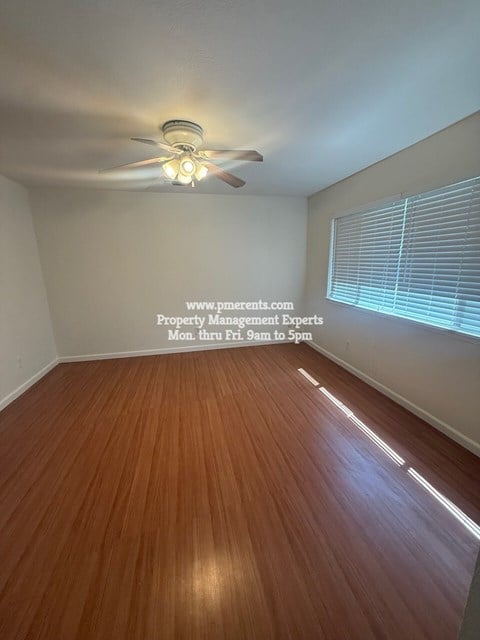 A room with wooden flooring and a ceiling fan.