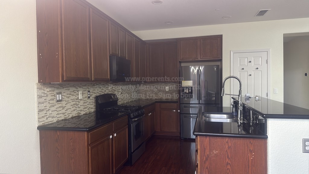 A kitchen with brown cabinets and a black counter top.