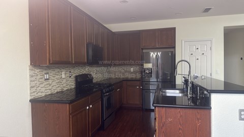 A kitchen with brown cabinets and a black counter top.