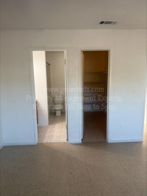 A room with two open doors leading to a bathroom and kitchen.