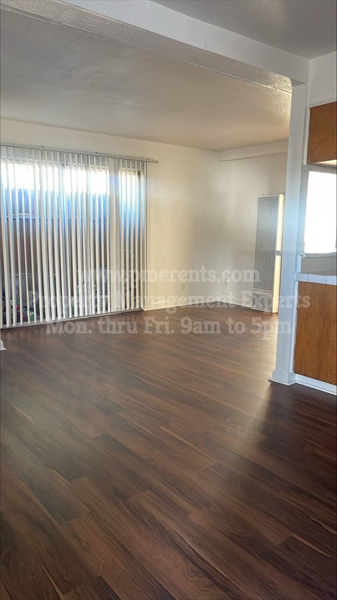 a living room with wood floors and a window and blinds