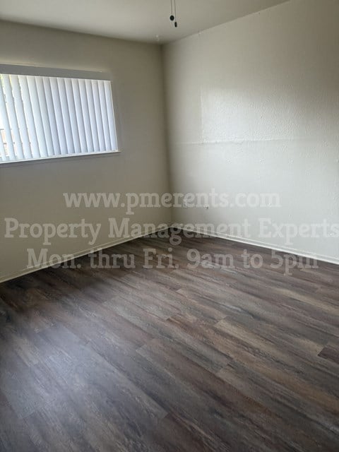an empty room with wooden floors and a window