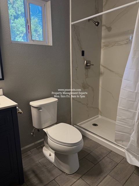 A white toilet in a bathroom with a window.