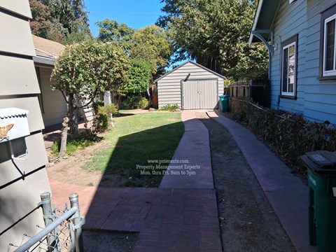 A residential area with a walkway and a sign for a property management company.