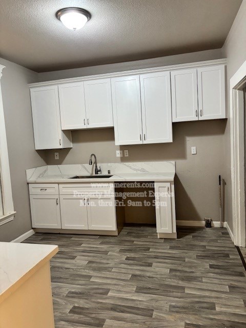 A kitchen with white cabinets and a marble countertop.