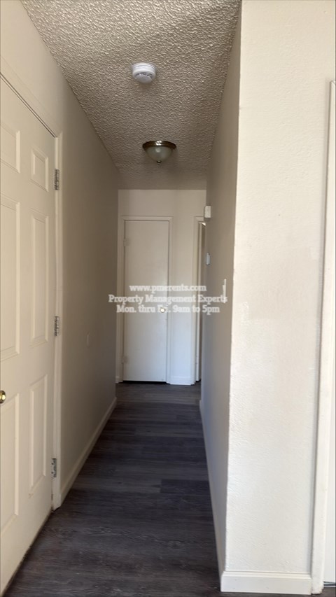 A long, narrow hallway with white doors and a light on the ceiling.