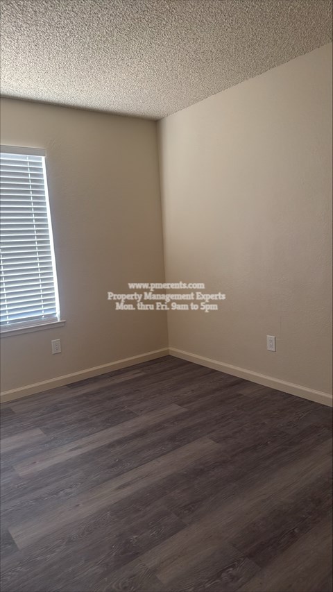 A room with wooden flooring and a window with blinds.