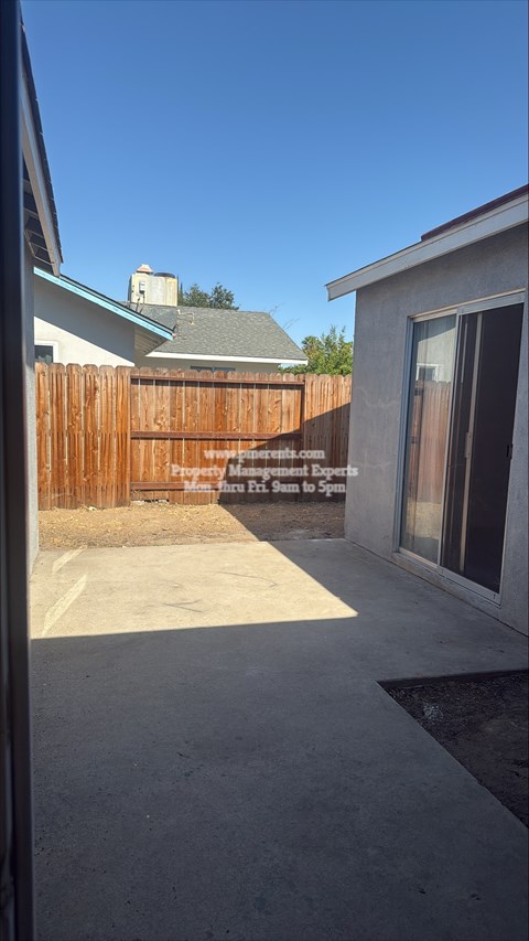 A backyard with a wooden fence and a house in the background.
