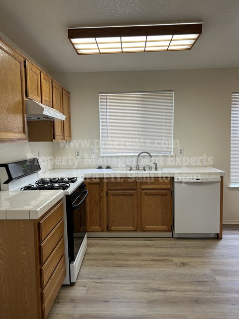 A kitchen with wooden cabinets and a white stove top oven.