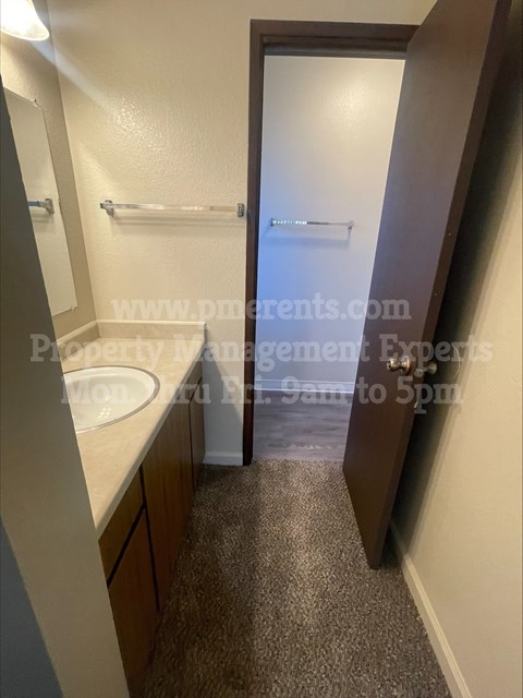 A bathroom with a sink, mirror, and towel rack.