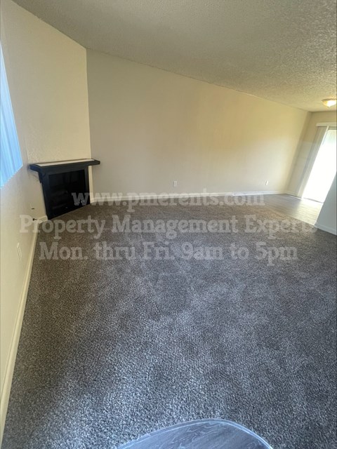 A room with a grey floor and a white wall with a black shelf on it.