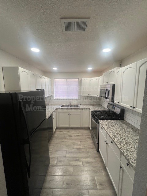 A kitchen with black appliances and white cabinets.