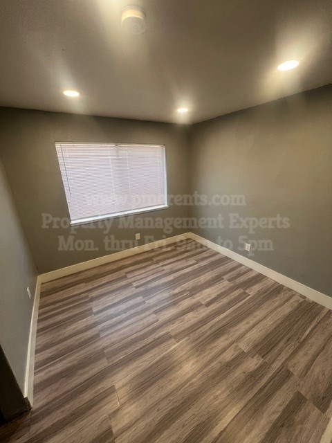 A room with wooden flooring and a window with blinds.