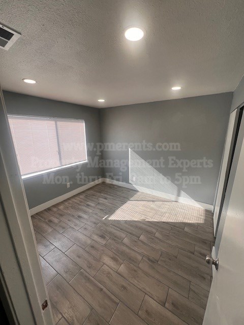 A room with a wooden floor and a window with blinds.