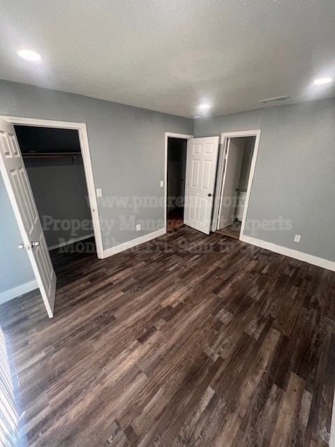 A room with wooden flooring and three doors.