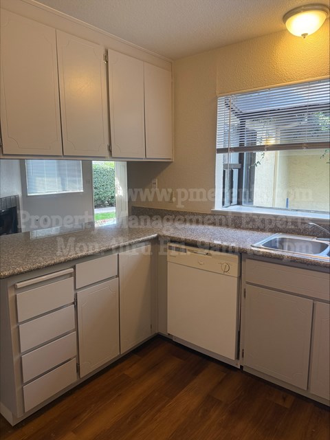 A kitchen with white cabinets and a granite countertop.